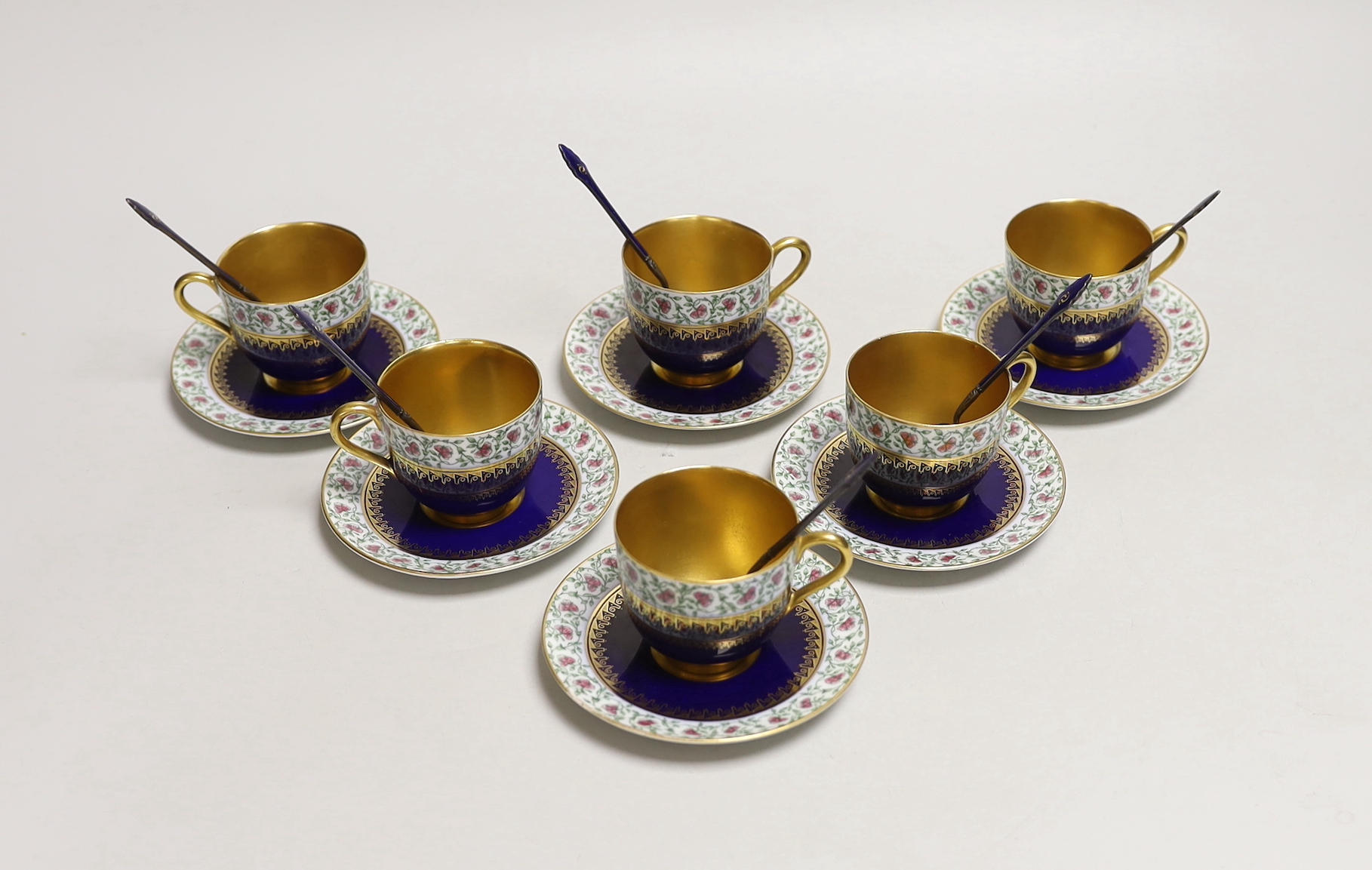 A set of six Royal Worcester porcelain coffee cups and saucers, together with a set of six silver and blue enamelled spoons